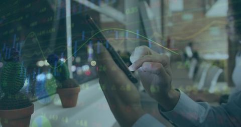 Professional tapping stylus on tablet with stock charts overlay in coworking space