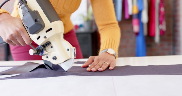 Fashion designer cutting fabric with electric fabric knife in workshop - Download Free Stock Images Pikwizard.com