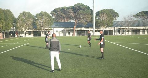 Youth soccer coach leads training session on school field