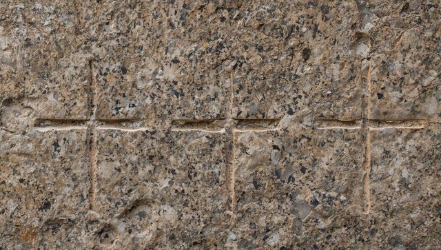 Four incised crosses carved into weathered stone slab with visible tool marks