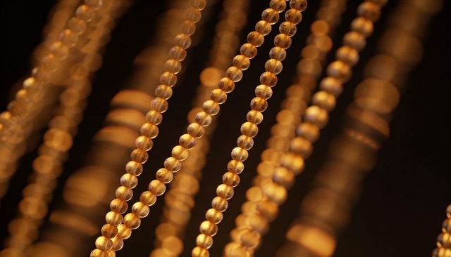 Hanging golden bead curtains gleaming with amber bokeh and translucent spherical highlights