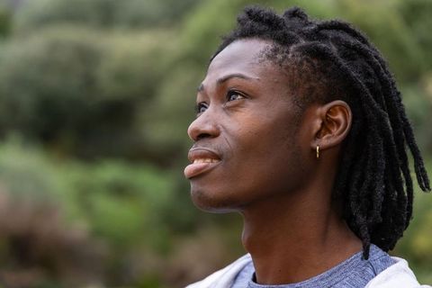 African American man gazing upward with dreadlocks and gold hoop earring in nature