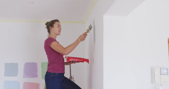 Woman Painting Interior Wall with Paint Samples in Background - Download Free Stock Images Pikwizard.com