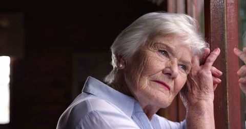 Thoughtful Senior Woman Looking Out Window Deep in Reflection