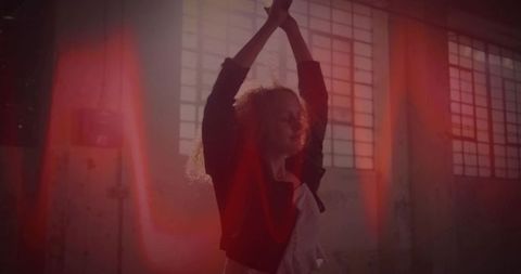 Expressive dancer in urban warehouse with dramatic light flares