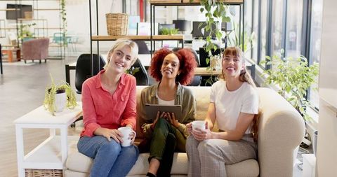 Diverse Female Colleagues Enjoy Coffee Break in Modern Office Lounge