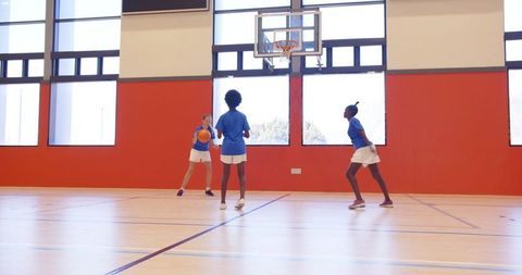 Young Girls Practicing Basketball in School Gym