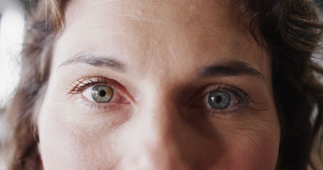 Vibrant close-up of a woman's eyes showcasing heterochromia; one eye is brown, and the other is blue. Useful for articles on human genetics, ophthalmology, beauty blogs focusing on unique features, and visual identity projects emphasizing individuality.