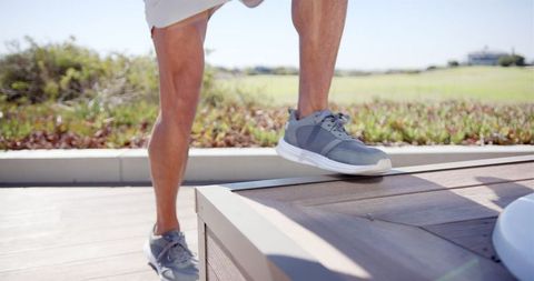 Person performing step-up exercise outdoors on sunny day