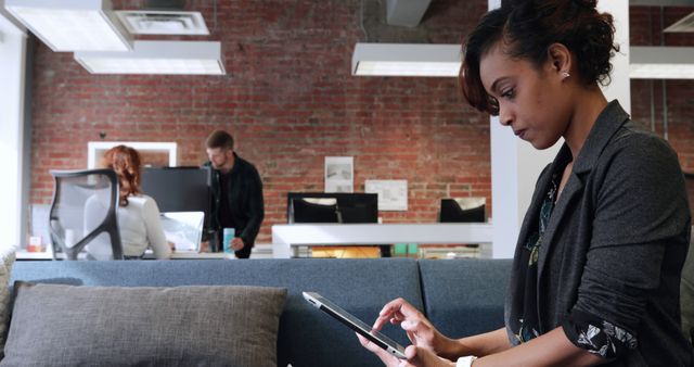 Professional Woman Using Tablet in Modern Office With Colleagues in Background - Download Free Stock Images Pikwizard.com