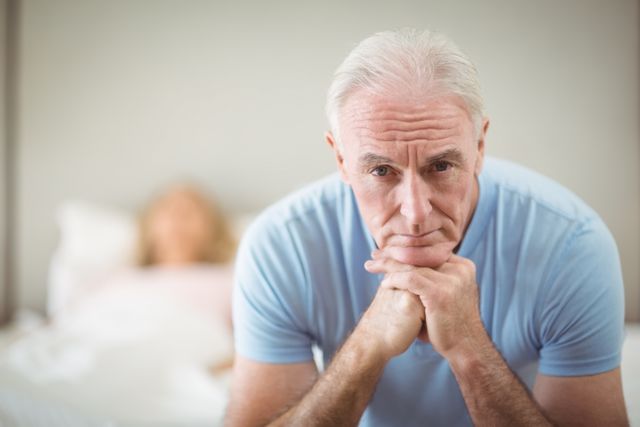 Portrait of worried senior man sitting at home