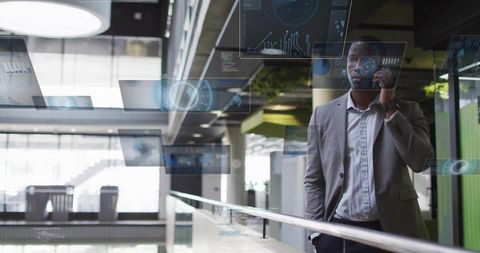Executive talking on phone while leaning on glass railing with holographic interface overlays