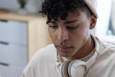 Young man in beanie with headphones concentrating indoors closeup portrait for study, work