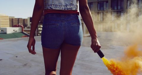 Young woman holding smoke bomb on rooftop
