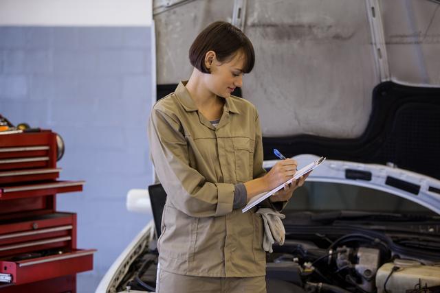 Female mechanic preparing a check list at the repair garage