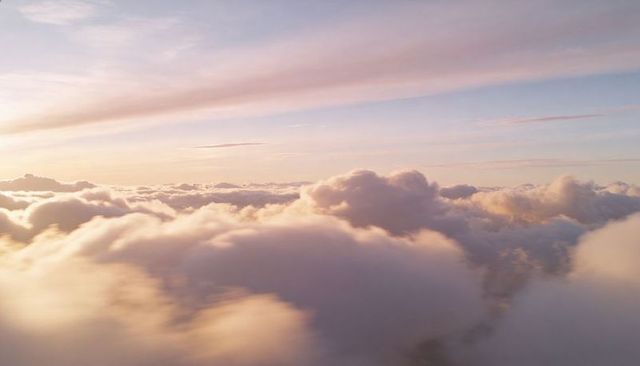 Sunlit Pastel Cloudscape Above Thick Cloud Bank at Sunrise, Ethereal Aerial Horizon
