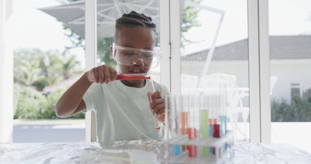 African american boy sitting at table doing chemistry experiments at home. Childhood, science and domestic life, unaltered.