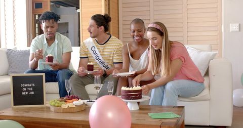 Friends celebrating new job with cake and snacks in living room