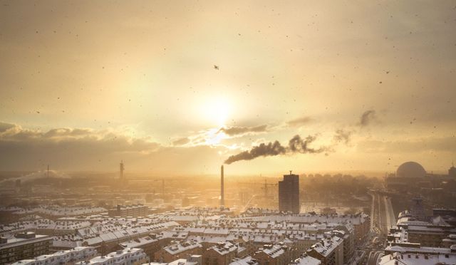 Cityscape with snow-covered buildings at sunset. Smoke is rising from a factory chimney, creating smog. Ideal for environmental awareness projects, urban lifestyle features, weather reports, and portfolios focusing on city infrastructure and pollution.