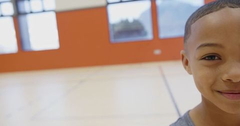 Smiling Boy in Gym with Basketball Court Background