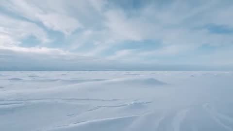 Slow advancing camera over polar plain revealing sastrugi, snowdrifts and expansive sea ice