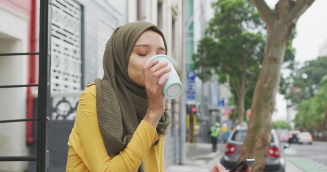 Young Woman in Hijab Enjoying Coffee Outdoors in Urban Setting - Download Free Stock Images Pikwizard.com