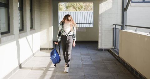 Teen Student Walking with Backpack in School Corridor