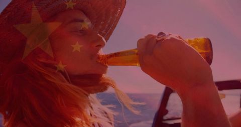 Man enjoying a beverage at sea with straw hat under clear sky