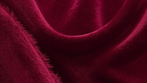 Plush burgundy velvet draping with soft pile, frayed edge and luxurious sheen