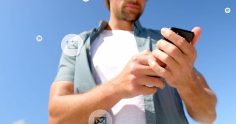 Caucasian man engaging with smartphone below clear blue sky