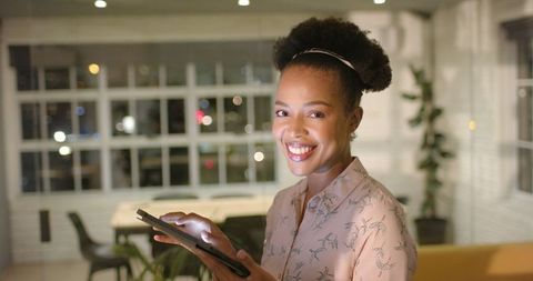 Smiling Businesswoman Using Tablet in Modern Office at Night