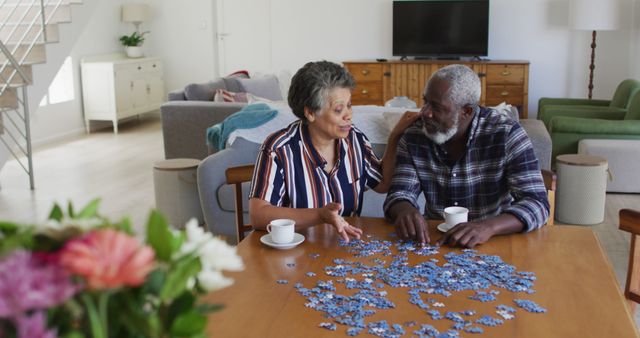 African american senior couple sitting by table doing puzzles drinking tea. senior retirement lifestyle friends socialising.