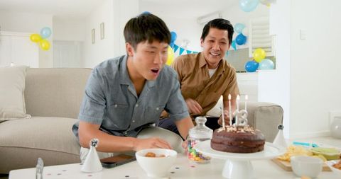 Friends celebrating birthday with cake in festive living room