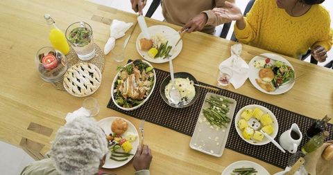 Multigenerational diverse family sharing homemade dinner around wooden dining table