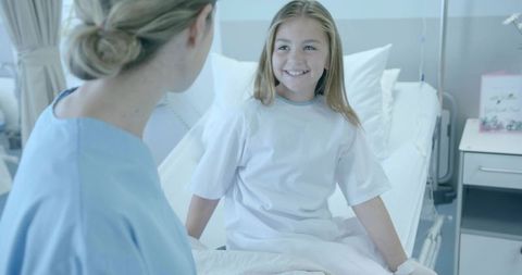 Smiling pediatric patient talking with nurse at hospital bed, IV line, compassionate care