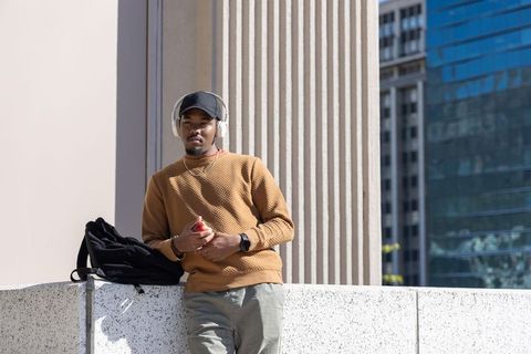 Urban chill lifestyle: african american man leaning on ledge listening with headphones