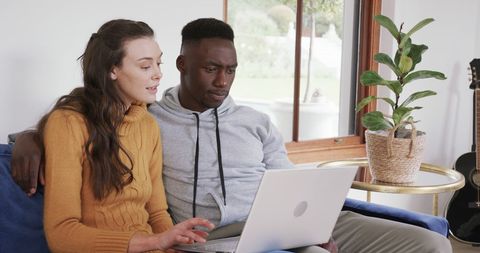 Happy Diverse Couple Browsing on Laptop at Home