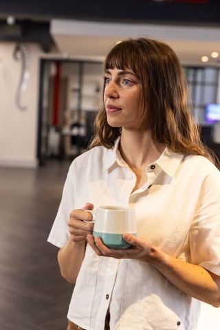 Professional Woman Sipping Coffee in Comfortable Office Environment