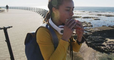 Female Traveler Enjoying Sandwich by Seaside Promenade