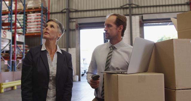 Warehouse managers are supervising the inventory using a laptop and a barcode scanner. This imagery is suitable for illustrating themes related to logistics, inventory management, technology integration in warehouses, teamwork, and business operations. Ideal for articles, advertisements, and brochures focused on efficient warehouse operations, logistics solutions, or professional team management.