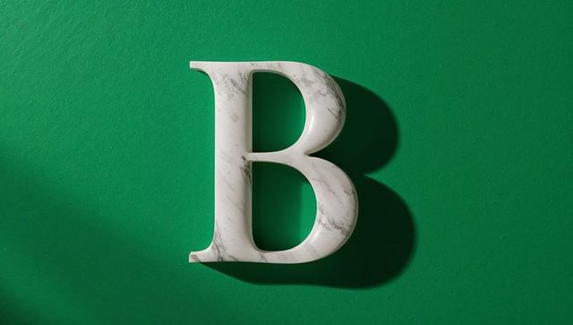 Marble letter b on vibrant green background casting shadow