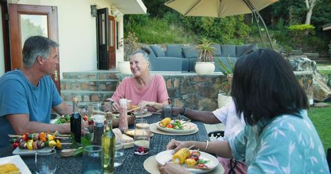 Diverse friends enjoy outdoor banquet at rustic patio