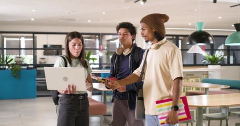 African american students collaborating over laptop in modern study lounge with headphones