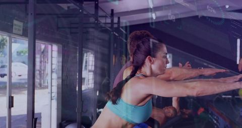 Woman reaching forward during group workout class in daylight gym with rig and mirrors