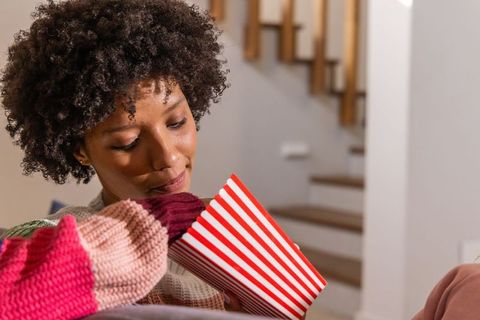 African american woman sharing popcorn with child on couch during family movie night