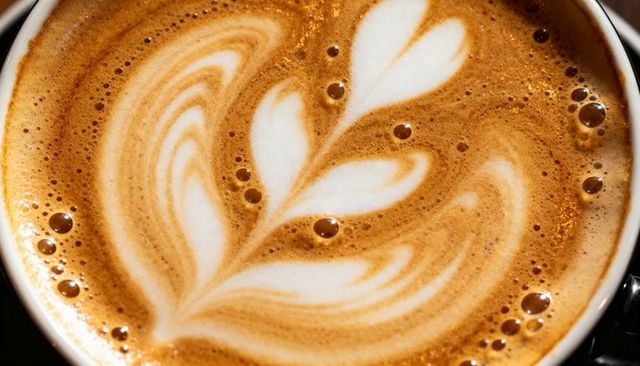 Macro latte art rosetta heart foam in ceramic cup, creamy crema bubbles, coffee texture
