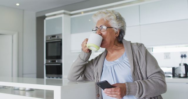 Senior Woman Enjoying Coffee While Using Smartphone in Modern Kitchen - Download Free Stock Images Pikwizard.com