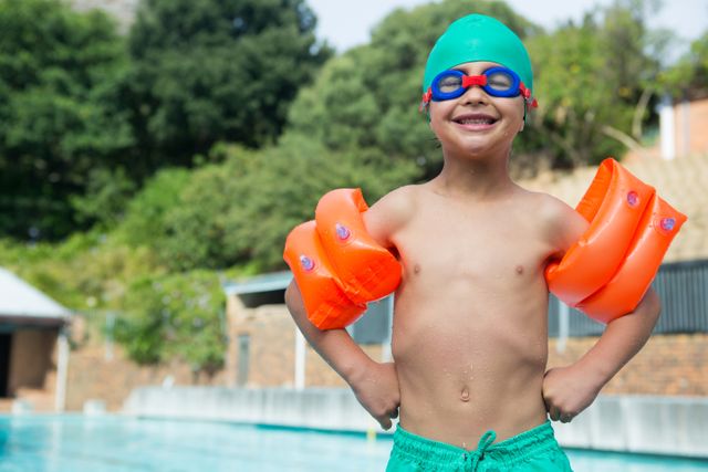 Portrait of boy wearing arm band standing at poolside