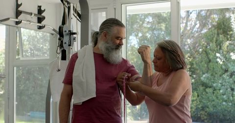 Senior Couple Sharing Laughs Measuring Arm in Home Gym