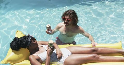 Relaxing couple enjoying drinks in a pool on a sunny day